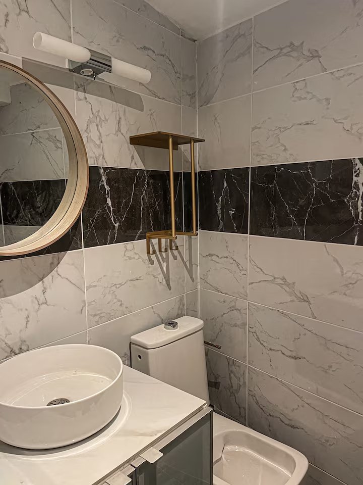 Salle d'eau en marbre avec vasque ronde et miroir cerclé de bois